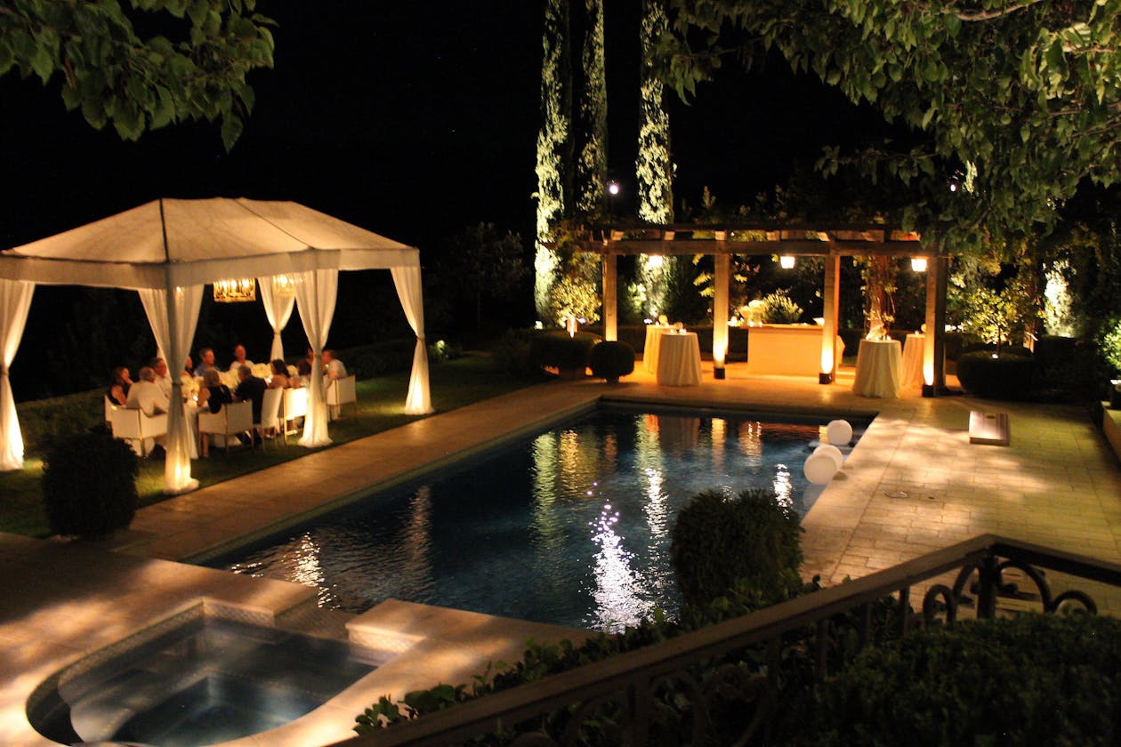 outdoor pool party 60th birthday at night with tented dinner table | PartySlate