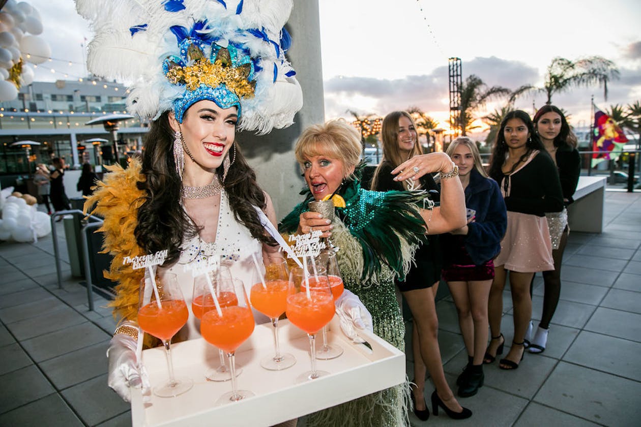 woman passing out cocktails at themed outdoor 60th birthday party | PartySlate