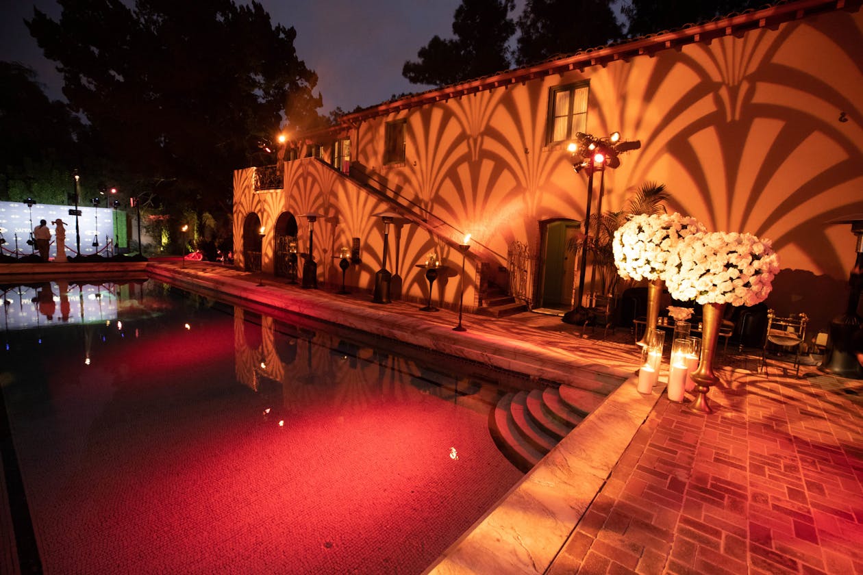 outdoor birthday party with orange lighting on the pool | PartySlate