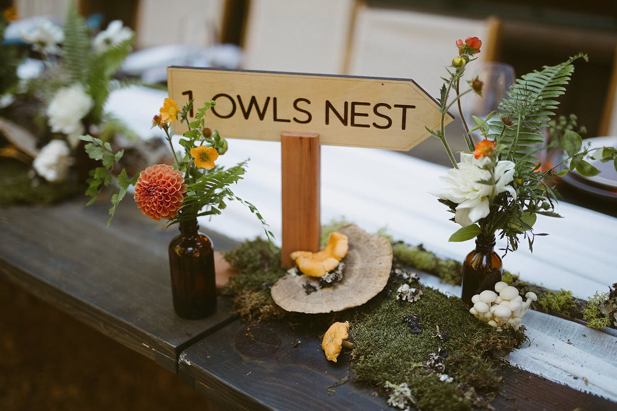 Organic moss centerpieces with wooden arrow table number | PartySlate