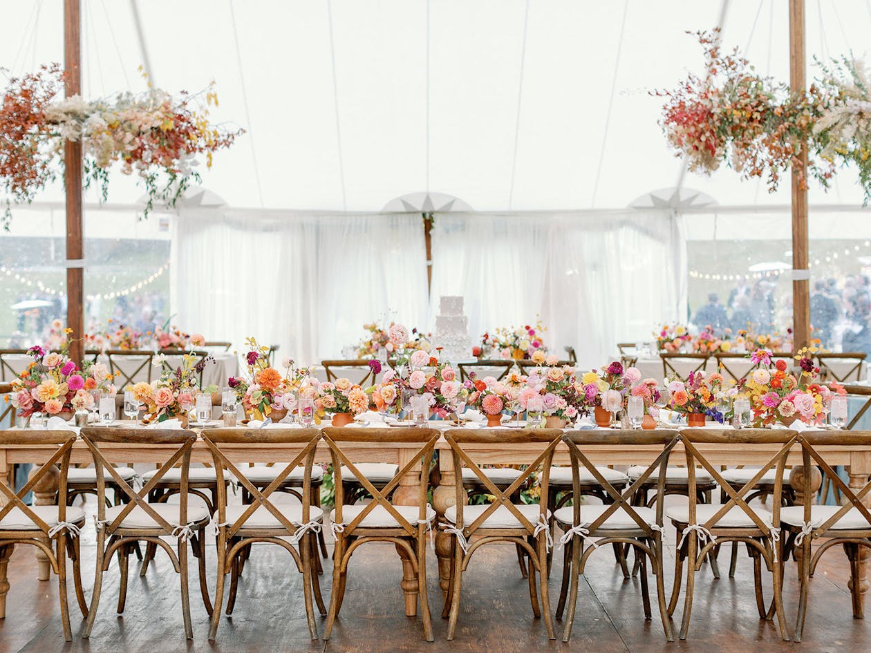 Summer tented wedding reception with warm-hued florals | PartySlate