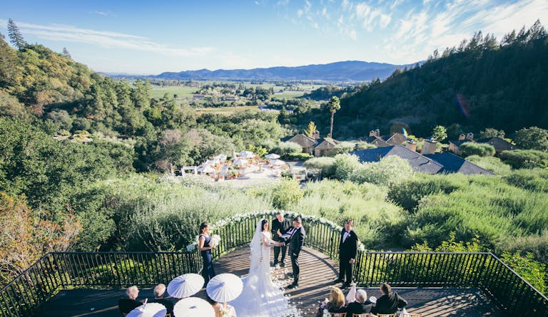 modern outdoor wedding in northern california wine country with green grass and views of the hills with couple standing at the alter | PartySlate