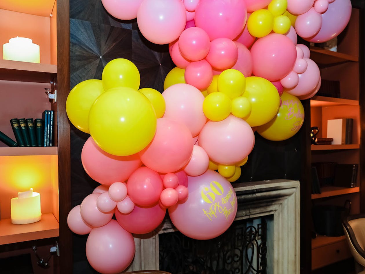indoor pink and yellow balloon installation at 60th birthday party | PartySlate