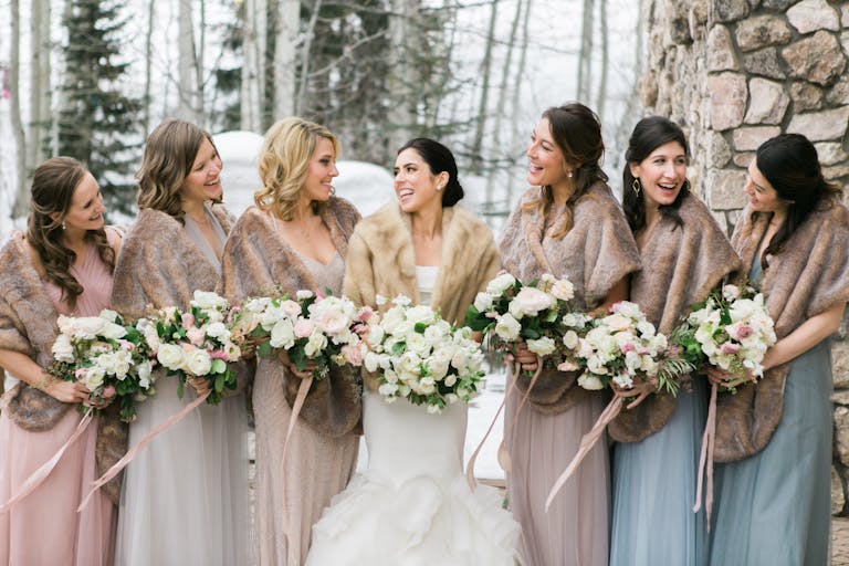 winter wonderland wedding with bridal party standing outside in fur coats | PartySlate