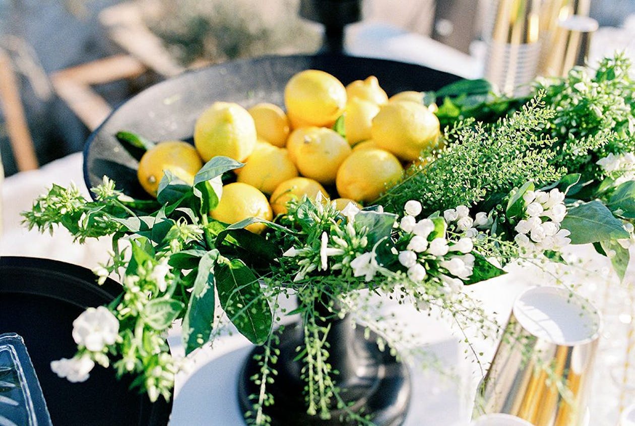 Centerpiece of bowl of lemons with greenery | PartySlate