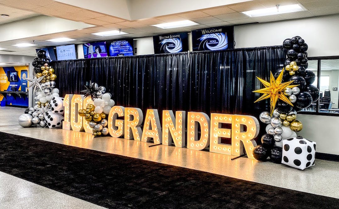 Manheim 100 Grander Auction with marquee signage and metallic balloons | PartySlate