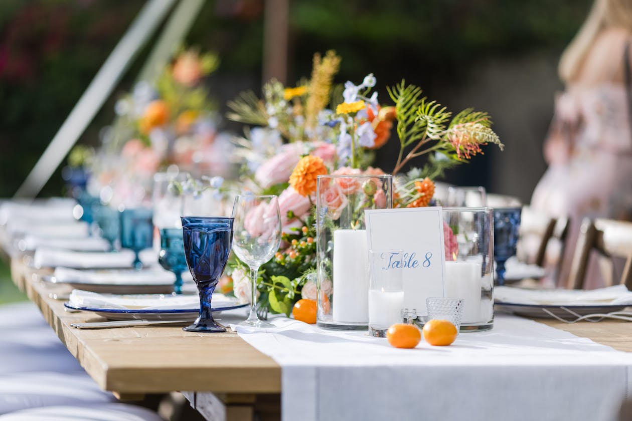 Colorful flower summer wedding centerpieces with bright blue goblets | PartySlate