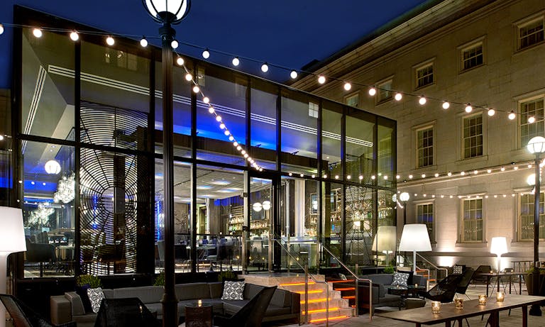 Dirty Habit at the Kimpton Hotel Monaco Washington DC with glass windows at the entrance and string lights over the patio | PartySlate