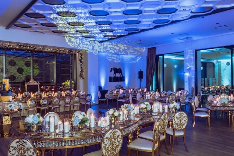 birthday party dinner at 51fifteen Cuisine & Cocktails in Houston with blue lighting, gold tables and chairs, and floral tablescapes | PartySlate