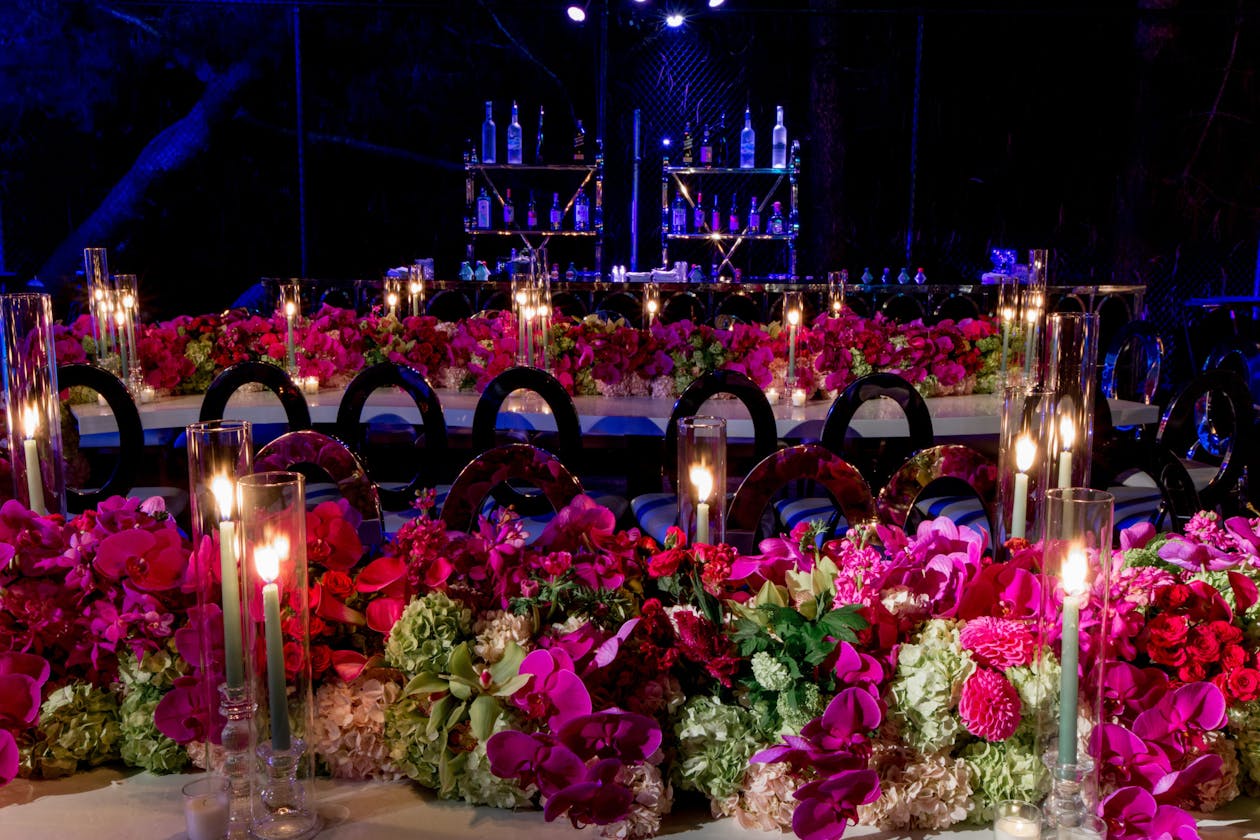 indoor party with blue lighting and red and pink flowers on tables | PartySlate