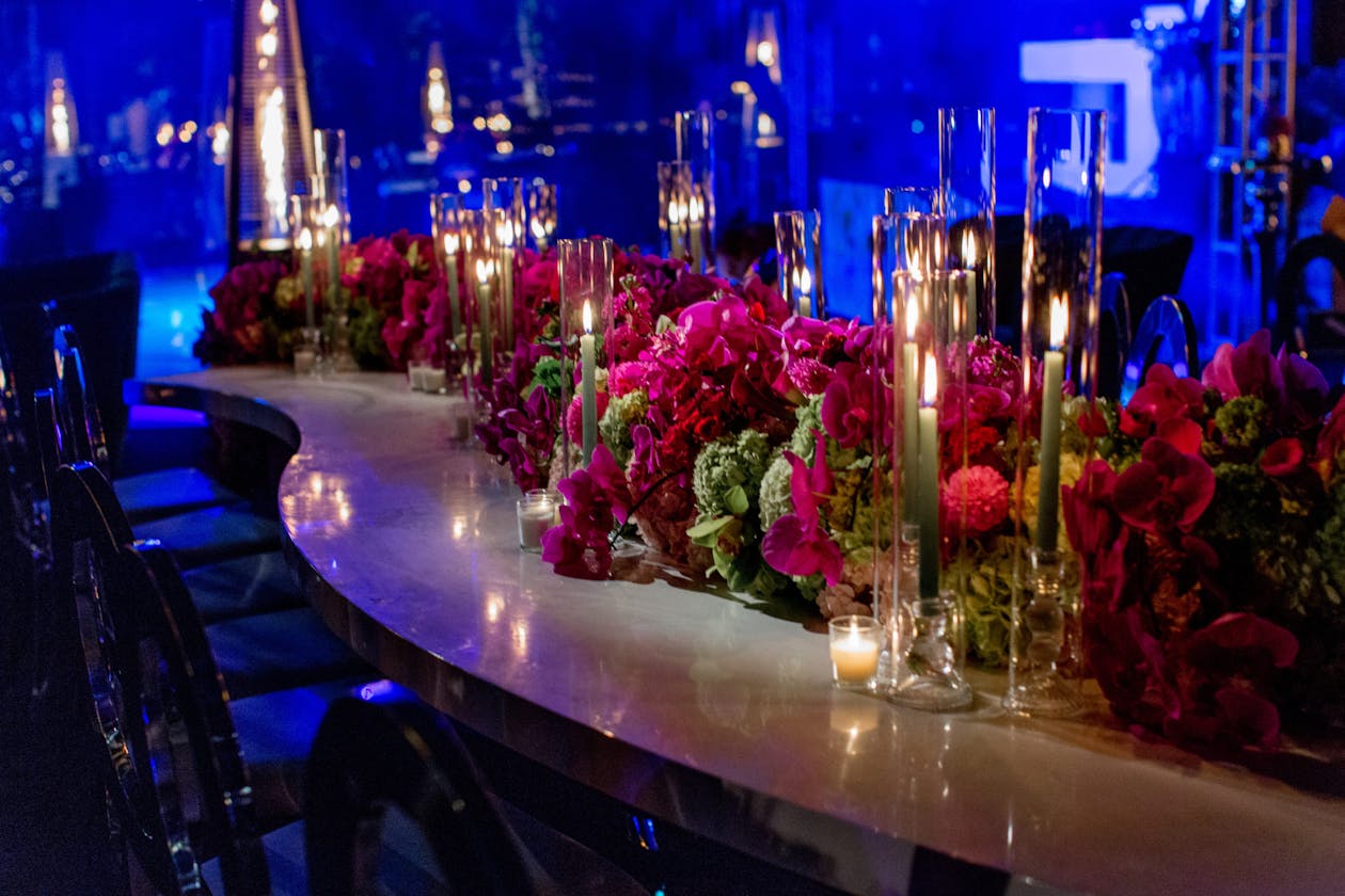 indoor party with blue lighting and red and pink flowers on tables | PartySlate