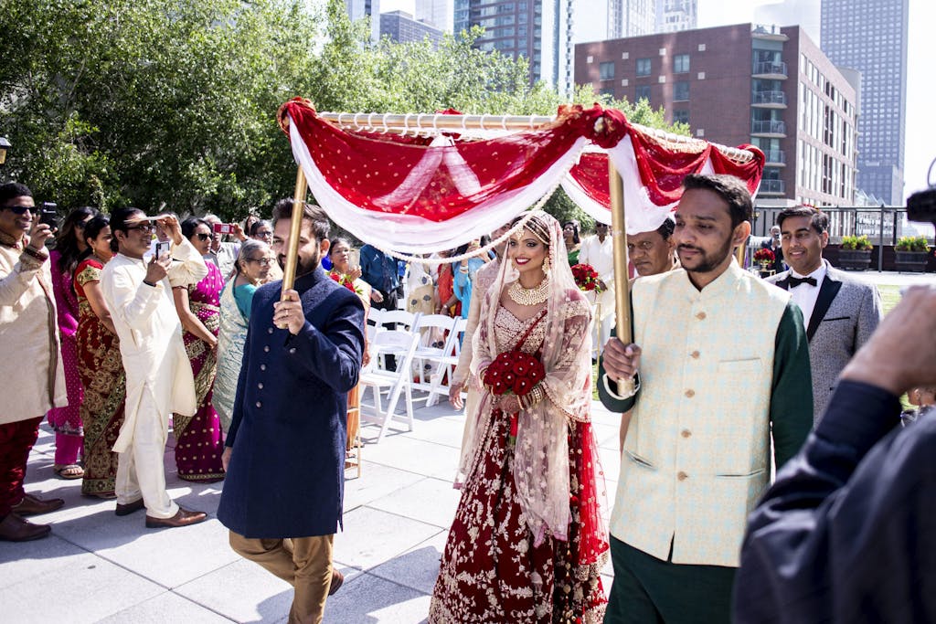 Bride is escorted to Mandap under red and white canopy during Kanya Aagaman | PartySlate