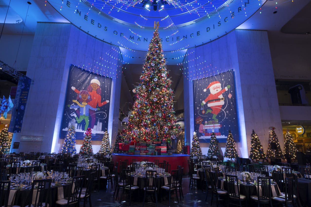 Corporate holiday party at Museum of Science and Industry with Giant Christmas Tree and Blue Uplighting | PartySlate