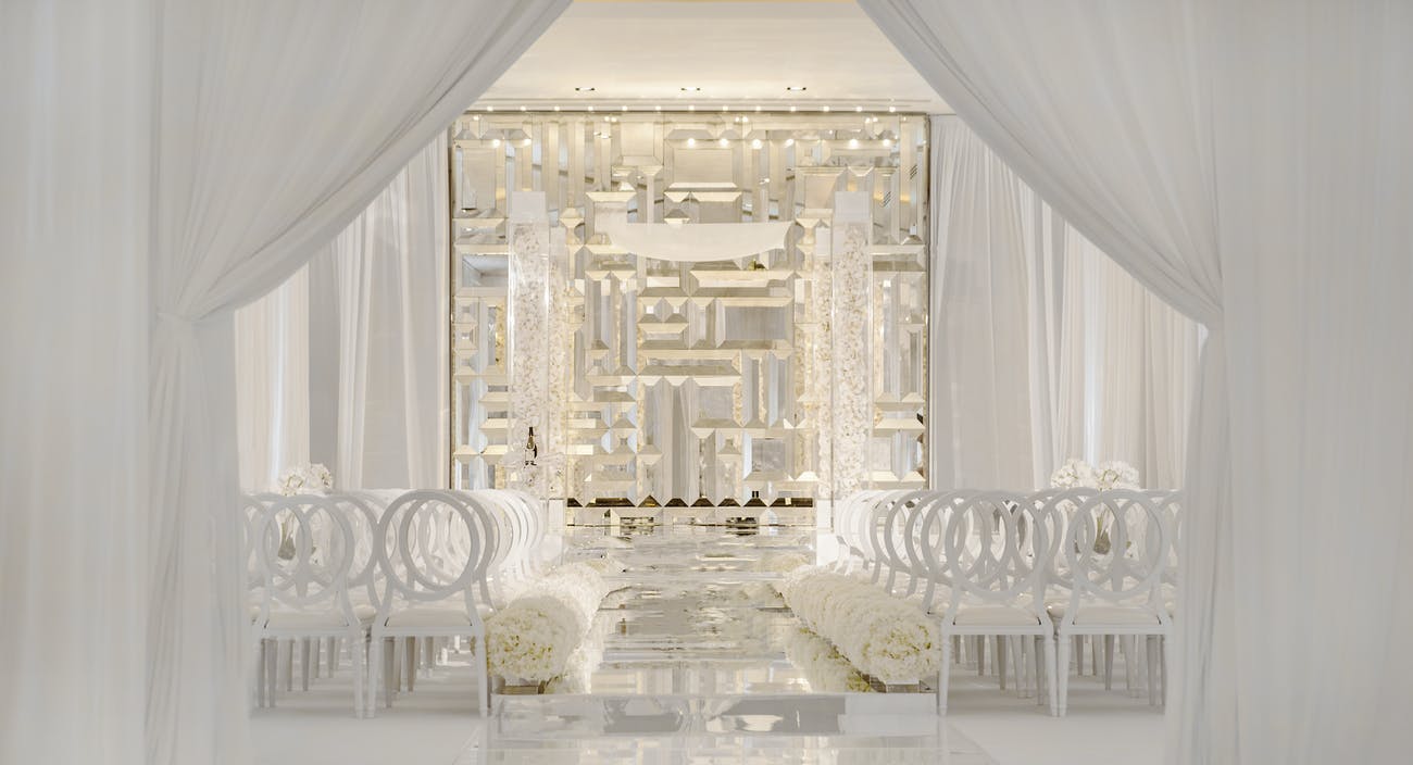 Modern, all-white wedding ceremony with mirrored backdrop