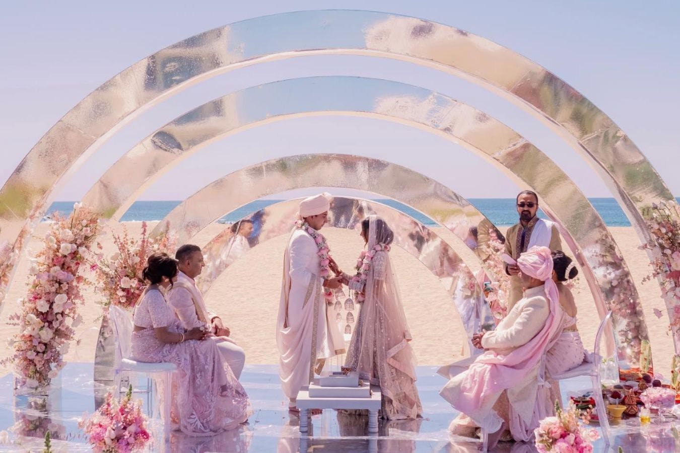 Beach South Asian wedding ceremony with four metallic arched mandap by Premini Events | PartySlate