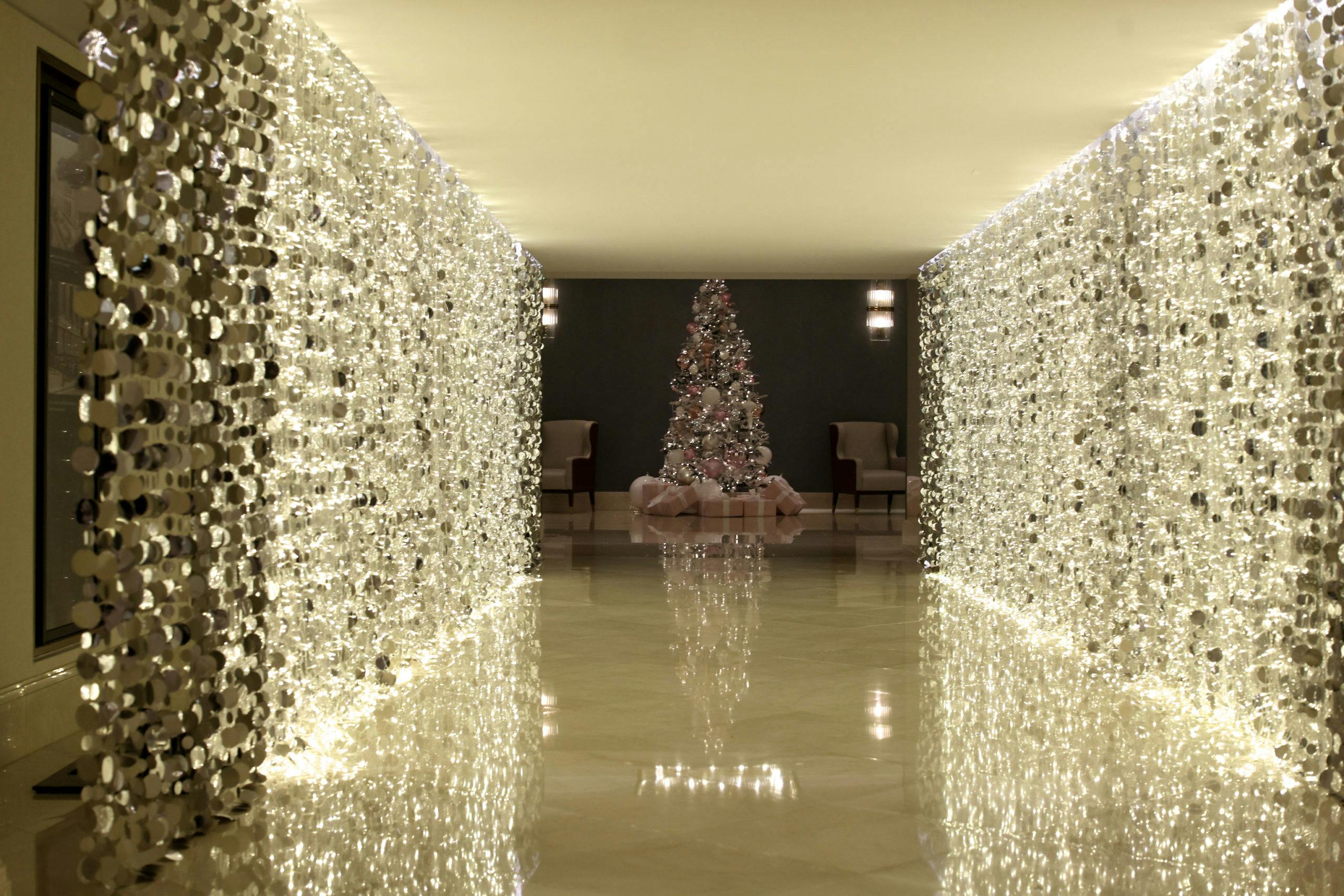 Twinkling light entrance to holiday party with Christmas tree decked in gold, a top winter party idea.