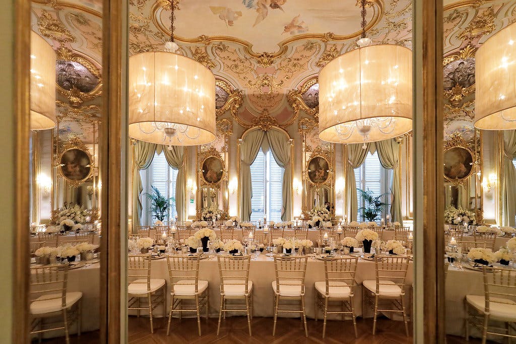 Wedding reception in a grand venue with regal ceiling décor.