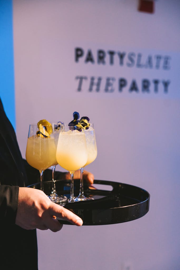 Cocktails topped with florals being served on a tray