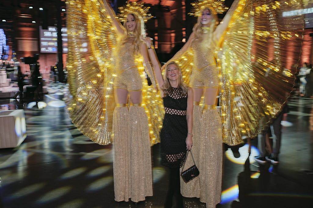 Guest posing with entertainers on stilts at a party